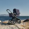 Bugaboo Fox 5 Renew tamsiai mėlynas kūdikių vežimėlis su lopšiu prie jūros ant uolų