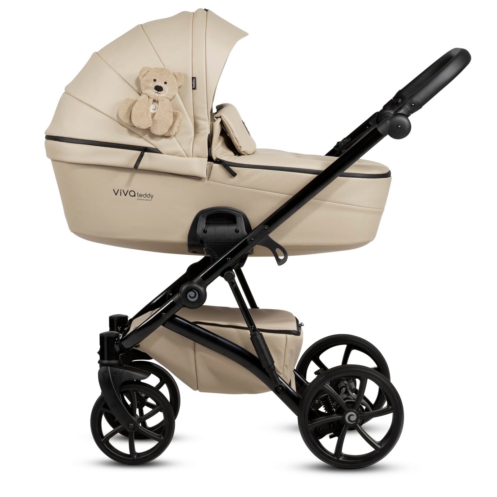 Bēšas bērnu ratiņi ar kulbu, melnu rāmi un lieliem riteņiem, dekorēti ar lāča mantiņu