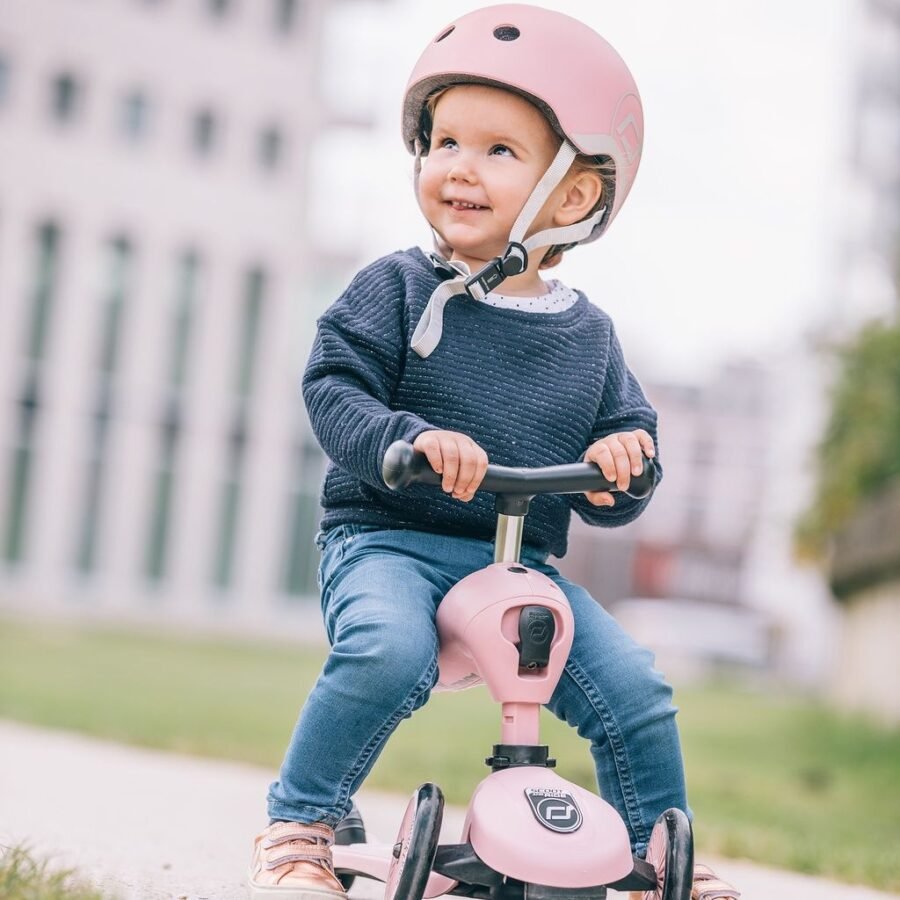 Rozā Scoot and Ride Highwaykick 1 skrejritenis ar bērnu un ķiveri