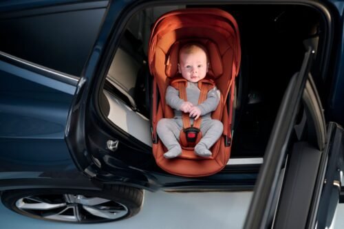 Oranžs Maxi-Cosi Coral autokrēsliņš ar zīdaini automašīnā