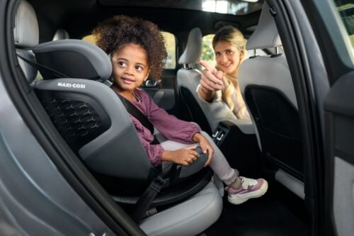 Pelēks Maxi-Cosi bērnu autokrēsliņš automašīnā, bērns piesprādzēts un mamma sēž blakus