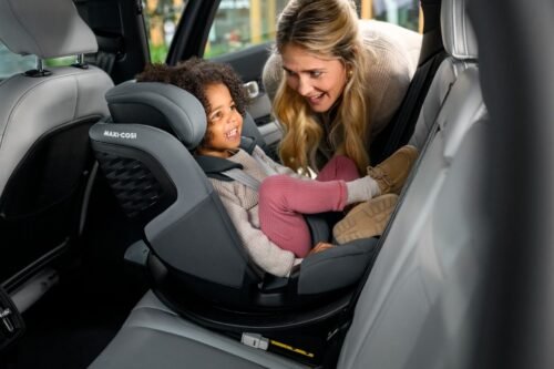 Maxi-Cosi bērnu autokrēsliņš automobilī ar bērnu un sievieti blakus, pelēkā krāsā, ar augstu atzveltni