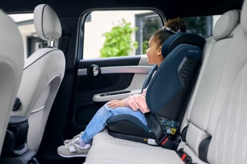 Tumši zils bērnu autokrēsliņš automašīnā, kurā sēž mazs bērns