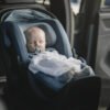 Thule zils mazuļa autokrēsliņš ar guļošu zīdaini automašīnā