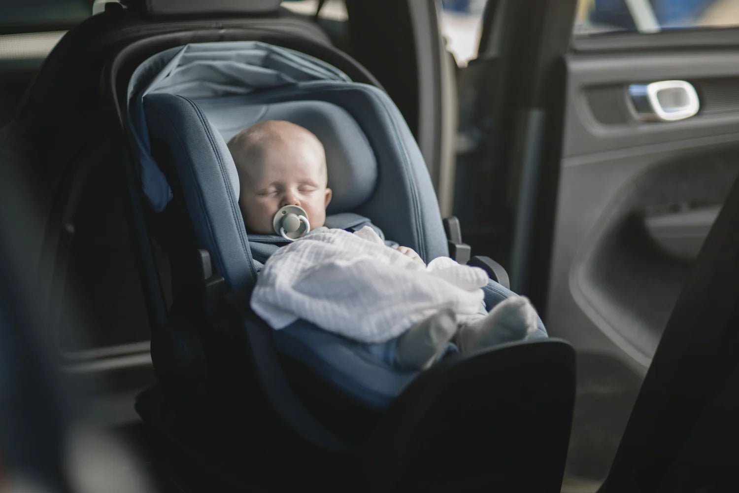 Thule zils mazuļa autokrēsliņš ar guļošu zīdaini automašīnā